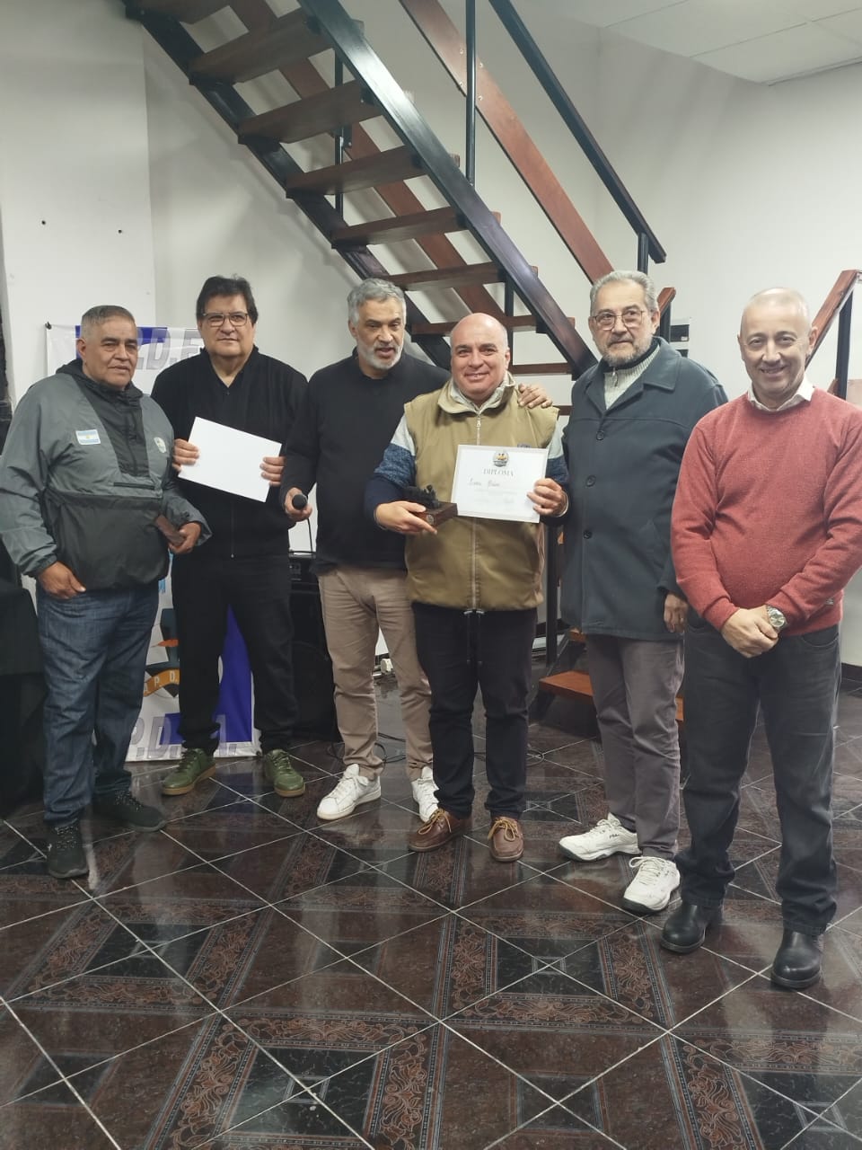 Un compañero jubilado recibe su diploma de reconocimiento junto a dirigentes de APDFA.